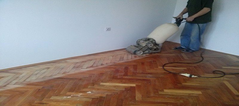 Majstor hobluje stari parket mašinom sa usisom